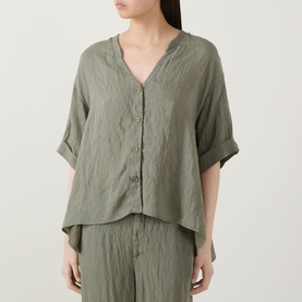 Model wearing Transit green V-neck shirt with button front and rolled sleeves, styled with matching wide-leg trousers