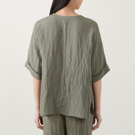 Model wearing Transit green relaxed-fit shirt, back view, with rolled sleeves and side vents, styled with matching green trousers.