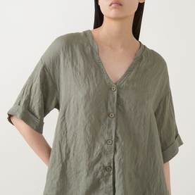 Model wearing Transit green V-neck shirt with button front and rolled sleeves, in a relaxed linen-effect fabric