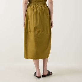 Model wearing Transit olive cotton midi skirt with elasticated waist and side pockets, styled with black flat sandals, rear view