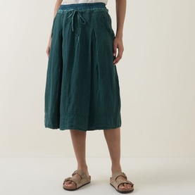 Model wearing Transit petrol linen-blend midi skirt with drawstring waist, styled with beige sandals.