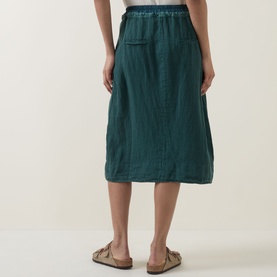 Model wearing Transit petrol linen blend midi skirt, back view, styled with tan leather sandals