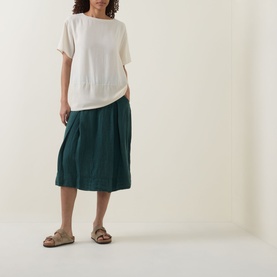 Model wearing Transit petrol linen-blend midi skirt with pleated detail, styled with cream top and beige sandals