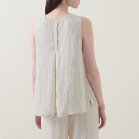 Model wearing Transit Pleated Textured Blouse in Sand, showing back view with button fastening, inverted back pleat and split side seams.