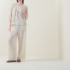 Model wearing Transit Pleated Textured Blouse in Sand, sleeveless with inverted pleats, styled with wide-leg trousers and flat shoes.