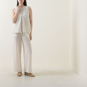 Model wearing Transit sand wide-leg trousers in cotton lyocell blend, styled with matching sleeveless top and flat shoes.