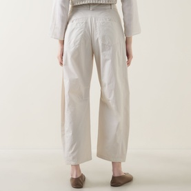 Model wearing Transit Cropped Barrel Leg Trousers in sand linen, rear view showing patch pockets and wide-leg silhouette, styled with brown loafers