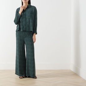Model wearing Transit Stripe Wide Leg Trousers in petrol, wide-cut silhouette with vertical stripe pattern, styled with matching shirt and black