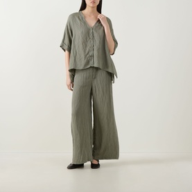 Model wearing Transit Textured Wide Leg Trousers in green, wide-leg silhouette, styled with matching green linen-look shirt and black flats.