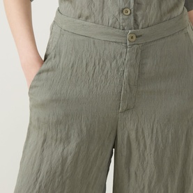 Model wearing Transit Textured Wide Leg Trousers in green, showing button fly fastening, side pocket and wide-leg silhouette in crinkled fabric