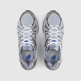 New Balance trainers in dark silver metallic grey, top-down view showing white laces, mesh upper, and blue NB logo on insole