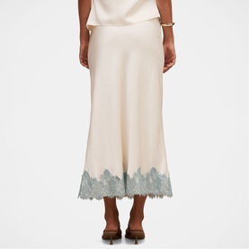 Model wearing Forever New champagne midi skirt with teal lace hem trim, styled with a cream top and brown heeled mules