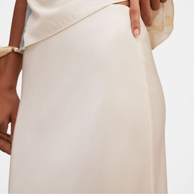 Model wearing Forever New champagne satin midi skirt, styled with a matching top and gold bracelet.
