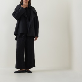 Model wearing Annette Gortz black viscose blouse with wide-leg black trousers and black flat shoes.
