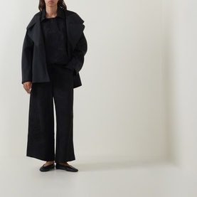 Model wearing Annette Gortz black oversized cotton jacket, styled with matching black wide-leg trousers and black ballet flats.