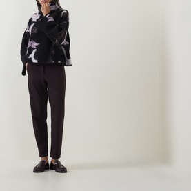 Model wearing Annette Gortz Still Dust merino wool knitwear with dark floral print, styled with dark tapered trousers and black loafers.