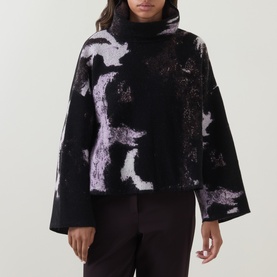 Model wearing Annette Gortz Still Dust merino wool turtleneck knit, black with lilac abstract print, wide sleeves, boxy fit