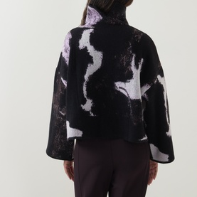 Model wearing Annette Gortz merino wool knitwear in Still Dust, abstract black and lilac pattern, wide sleeves, back view
