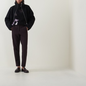 Model wearing Annette Gortz Still Dust merino wool knitwear with dark tailored trousers and dark loafers.