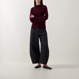 Model wearing Annette Gortz merlot merino wool turtleneck knit, styled with wide-leg dark trousers and black ballet flats.