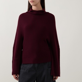 Model wearing Annette Gortz merlot merino wool ribbed knit jumper with turtleneck and wide sleeves, styled with dark trousers.