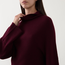 Model wearing Annette Gortz merlot merino wool ribbed knit jumper with funnel neck, close-up detail shot.