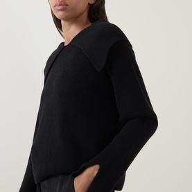 Model wearing Annette Gortz black merino wool knit with wide open collar, long sleeves, relaxed fit.