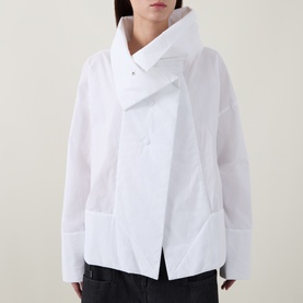 Model wearing Annette Gortz white cotton shirt with asymmetric wrap collar and front patch pockets, styled with dark trousers