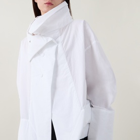 Model wearing Annette Gortz white cotton shirt with asymmetric draped collar and structured puff sleeves