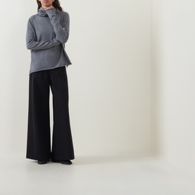 Model wearing Annette Gortz Melange merino wool turtleneck top, styled with wide-leg black trousers