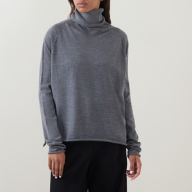 Model wearing Annette Gortz merino wool turtleneck top in grey melange, styled with black wide-leg trousers
