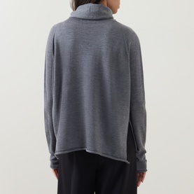 Model wearing Annette Gortz merino wool top in melange grey, showing rear view with relaxed fit and rolled turtleneck collar.