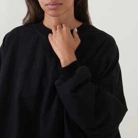 Model wearing Annette Gortz black silk top, close-up of relaxed neckline and wide sleeve detail.