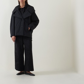 Model wearing Annette Gortz black wide-leg cotton trousers, styled with a black oversized jacket and flat shoes.