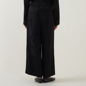 Model wearing Annette Gortz black wide-leg cotton trousers with elasticated waist, styled with a black top and flat shoes.