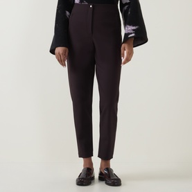 Model wearing Annette Gortz cocoa cotton trousers with a floral kimono-sleeve top and black loafers.