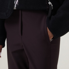 Model wearing Annette Gortz cocoa brown tailored trousers with front pleat detail and side pocket, styled with black textured jacket.