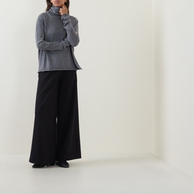 Model wearing Annette Gortz black wide-leg cotton trousers, styled with a grey turtleneck top and black flat shoes.