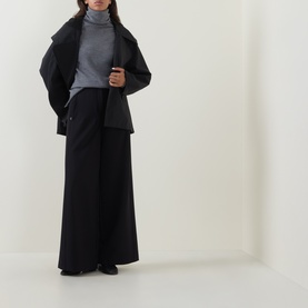 Model wearing Annette Gortz black wide-leg cotton trousers, styled with a grey roll-neck top and black oversized jacket.