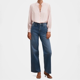 Model wearing Forever New blush pink long-sleeve blouse with ruffle neckline, styled with wide-leg blue jeans and tan heeled mules.