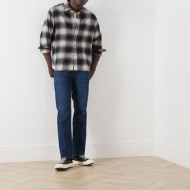 Model wearing Citizens of Humanity 3049 dark indigo straight jeans, styled with a black and white check overshirt and black canvas high-top trainers.