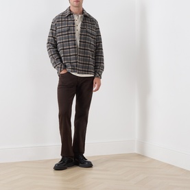 Model wearing Citizens of Humanity Straight Jeans in Tobacco, styled with a grey plaid overshirt and black leather shoes.