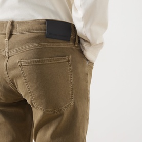 Model wearing Citizens of Humanity straight jeans in dark khaki, rear view showing back pockets and leather patch detail.