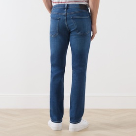 Model wearing Citizens of Humanity Gage Slim Leg Jeans in Watson mid wash, rear view showing logo patch and tobacco stitching
