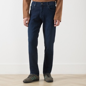Model wearing Citizens of Humanity straight jeans in Indio dark blue wash, styled with grey trainers and a tan top.