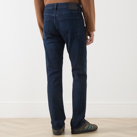 Model wearing Citizens of Humanity 3049 straight jeans in Indio dark indigo wash, rear view, styled with green trainers.