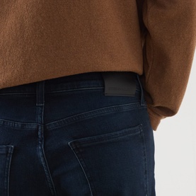 Model wearing Citizens of Humanity straight jeans in Indio dark wash, styled with a camel knit sweater. Close-up rear view showing back pocket detail.
