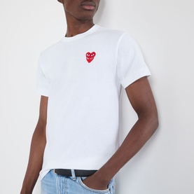 Model wearing Comme Des Gar&ccedil;ons Play Double Heart Embroidered Logo T-Shirt in white, with red double heart chest logo, styled with blue jeans.