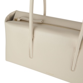 DeMellier Stockholm Shoulder Bag in Chalk grained leather, close-up showing gold-tone hardware and zip fastening with tubular handles