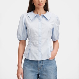 Model wearing Forever New soft blue puff sleeve shirt with oversized collar and cinched waist, styled with light wash jeans.